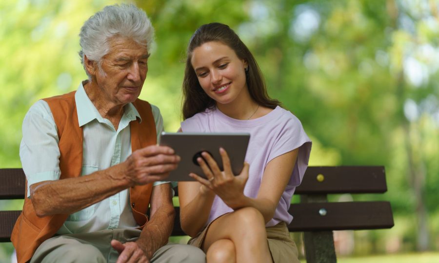 Caregiver helping senior man to shop online on tablet. The risk of online shopping scams targeting older people. Caregiver helping senior man to shop online on a tablet. The risk of online shopping scams targeting older people.
